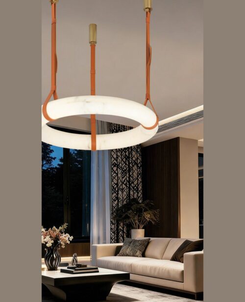 Gece ışığında salon köşesinde asılı, turuncu deri kayışlı ve alabaster taşlı 40×10 cm yuvarlak avizenin görünümü